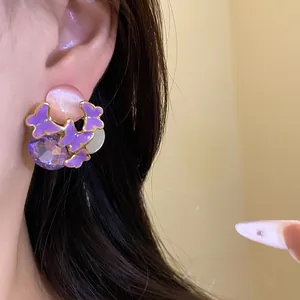 Detailed macro view of purple enamel butterfly stud earrings with faceted purple gemstone detail