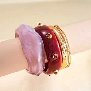 Close-up of vintage resin and gold-toned metal bangle set with studs and marbling.