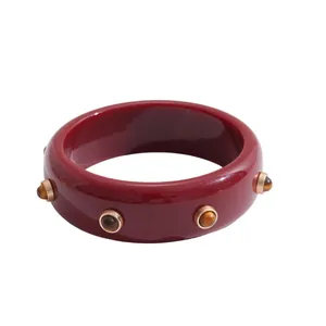 Professional studio shot of a vintage dark red resin bangle bracelet with golden stud accents