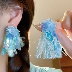 Primo piano di eleganti orecchini a fiore in resina con nappe in nastro colorato vivace