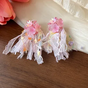 Dettaglio macro di eleganti orecchini a fiore in resina rosa con nappe di nastro