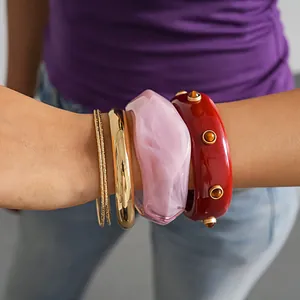 Detailed close-up of a 4-piece vintage resin and gold-toned bangle set worn on a wrist