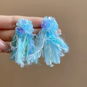 Dettaglio di eleganti orecchini a lobo in resina blu con raffinate frange di nappine in pizzo