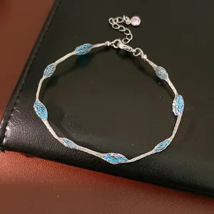 Detailopname van een zilveren mesh armband met blauwe zirkonia stenen op zwart leer