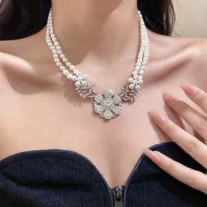 Elegant double-layered pearl necklace featuring a large sparkling rhinestone flower pendant
