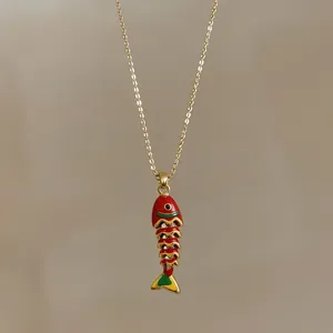 Dettaglio di un ciondolo a forma di pesce articolato in smalto rosso su catena d'oro