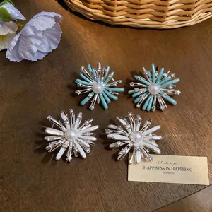 Fireworks-style zircon pearl stud earrings with colorful enamel on a wooden surface