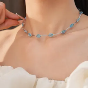 Detailopname van een minimalistische zilveren mesh choker met blauwe gradiënt ovale kralen.