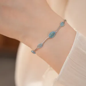 Detailopname van een delicate zilveren mesh armband met blauwe stenen op de pols