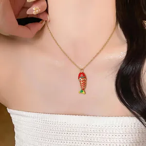 Dettaglio di una collana in acciaio dorato con un ciondolo a forma di pesce in smalto rosso