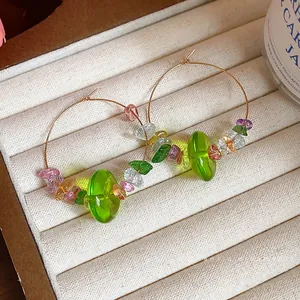 Boucles d'oreilles créoles printanières en résine verte avec perles colorées sur plateau