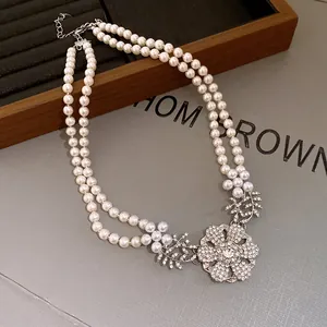 Detail of double-strand pearl necklace with an elegant rhinestone flower pendant