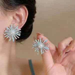 Detail view of blue enamel firework stud earrings featuring zircon and a central pearl.