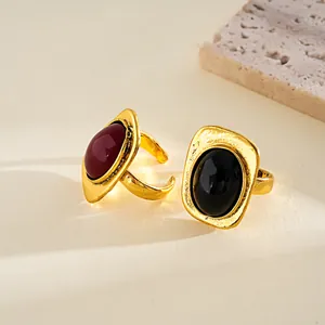 Detalle de anillos dorados vintage con piedras rojas y negras geométricas