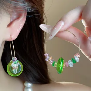 Vue détaillée de créoles en perles de résine verte avec des touches de pierres colorées