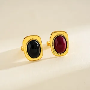 Detalle de anillos vintage dorados con piedras ovaladas de resina en color negro y granate