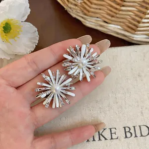 Close-up of white firework stud earrings with center pearl and small zircon stones