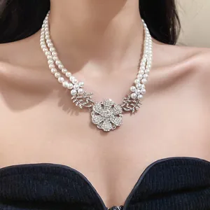 Detailed close-up of a double-strand pearl necklace with a crystal flower pendant.