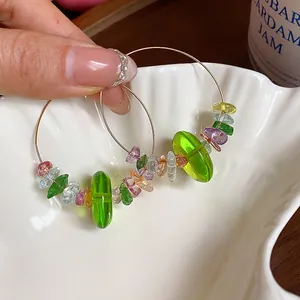 Vue détaillée des boucles d'oreilles créoles en perles de résine verte et cristal