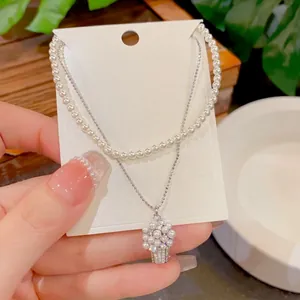 Dettaglio di collana di perle a doppio strato con ciondolo a cesto di fiori in zircone