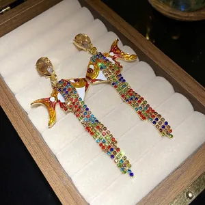 Funkelnde bunte Fisch-Quastenohrringe mit Strass und Emaille in einer Schmuckschatulle.