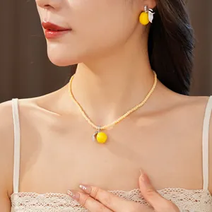 Vista detallada del conjunto de joyas con collar colgante de limón y pendientes amarillos