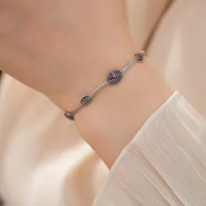 Detailweergave van een zilveren mesh-armband met donkerpaarse zirkoonaccenten