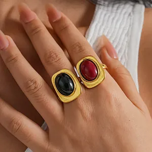 Primer plano de anillos de oro vintage con piedras ovaladas negras y rojas en la mano.
