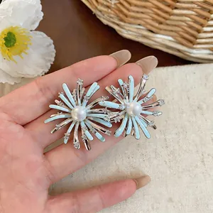 Detail view of fireworks stud earrings with zircon and light blue enamel pearls