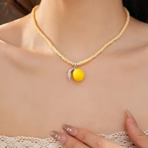 Primer plano de un collar de limón de resina con hojas de circón y cuentas.