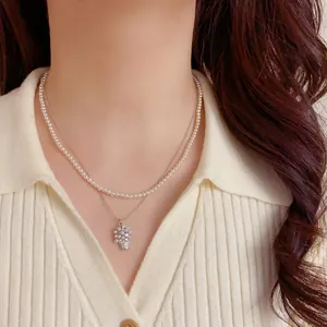 Dettaglio di una collana di perle a doppio strato con un ciondolo a cesto di fiori