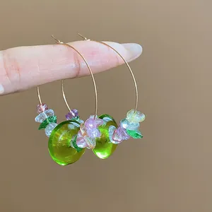 Détail de boucles d'oreilles créoles en résine verte avec perles