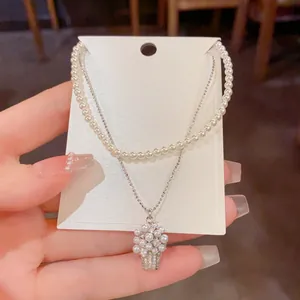 Elegante primo piano di una collana di perle a due strati con cesto di fiori pendente