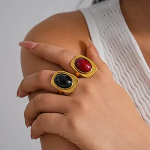 Primer plano de anillos abiertos dorados vintage con piedras ovales rojas y negras.