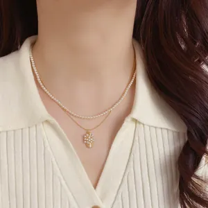 Elegante collana a doppio strato con perle e ciondolo a cesto di fiori dorato su una modella