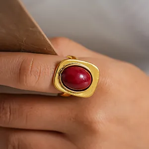 Detalle de un anillo dorado vintage con una gran piedra roja ovalada.