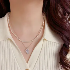 Primo piano di una collana di perle a doppio strato con ciondolo a cesto di fiori