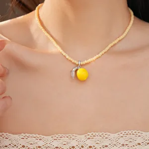 Primer plano de un collar con colgante de limón amarillo y cuentas de resina crema