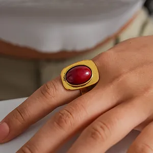 Primer plano detallado de un anillo dorado vintage con una gran piedra roja ovalada.