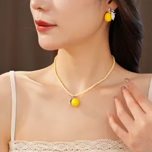 Detalle de collar y pendientes con colgante de limón de resina en el modelo