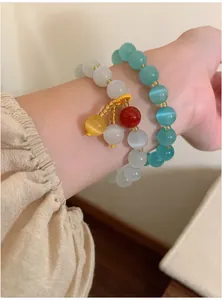 Detailed view of cat's eye stone beaded bracelets with colorful pendant on wrist
