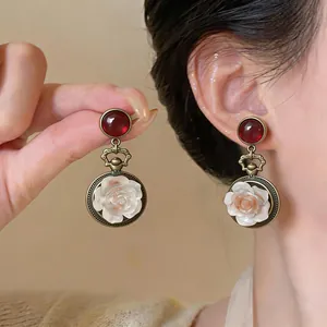 Dettaglio di orecchini vintage in resina con rosa, cabochon rosso e finitura in bronzo