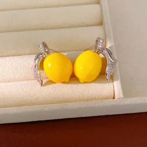 Primer plano exquisito de pendientes de limón con circonitas brillantes y resina amarilla.