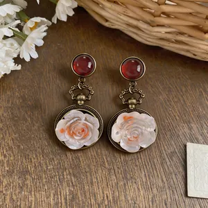 Primo piano di orecchini vintage in bronzo con cabochon rossi e fiori intagliati