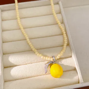 Primer plano de collar con colgante de limón de resina y circón en bandeja de joyería