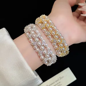 Close-up of multi-layer pearl bracelets with sparkling zircon flower charms on wrist