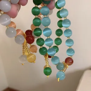 Handheld display of colorful cat-eye beaded bracelets with elegant tassel pendants