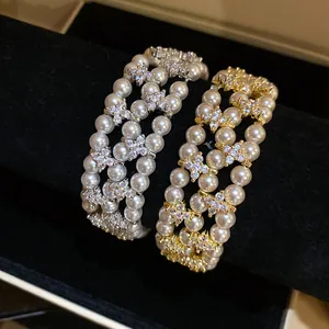 Macro detail of multi-layer pearl and zircon floral bracelets in gold and silver tones