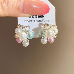 Détail de boucles d'oreilles nœud élégantes avec perles colorées et oxydes de zirconium