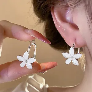 Elegant silver needle hoop earrings with white resin flowers, minimalist design for women.